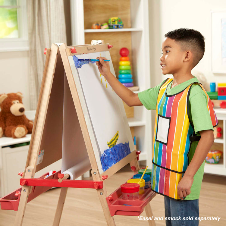 A kid playing with The Melissa & Doug Easel Paper Roll - 17 Inches Wide, 75 Feet Long for Painting, Drawing, Art and Craft Projects for Kids