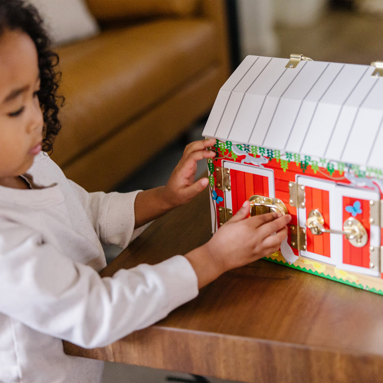 A kid playing with The Melissa & Doug Latches Wooden Activity Barn with 5 Doors, 4 Play Figure Farm Animals