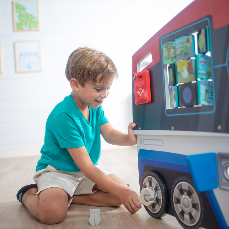 A kid playing with The Melissa & Doug PAW Patrol Wooden PAW Patroller Activity Center Multi-Sided Play Space