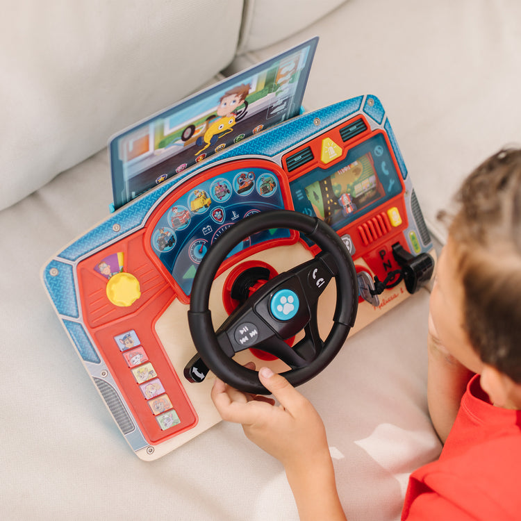 A kid playing with The Melissa & Doug PAW Patrol Rescue Mission Wooden Dashboard