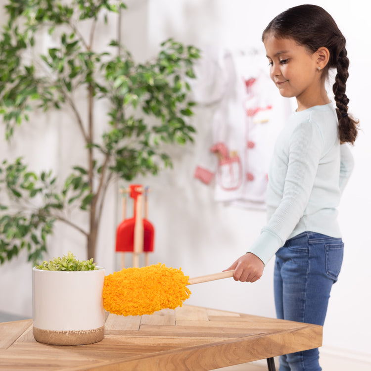 A kid playing with The Melissa & Doug Dust! Sweep! Mop! 6-Piece Pretend Play Cleaning Set