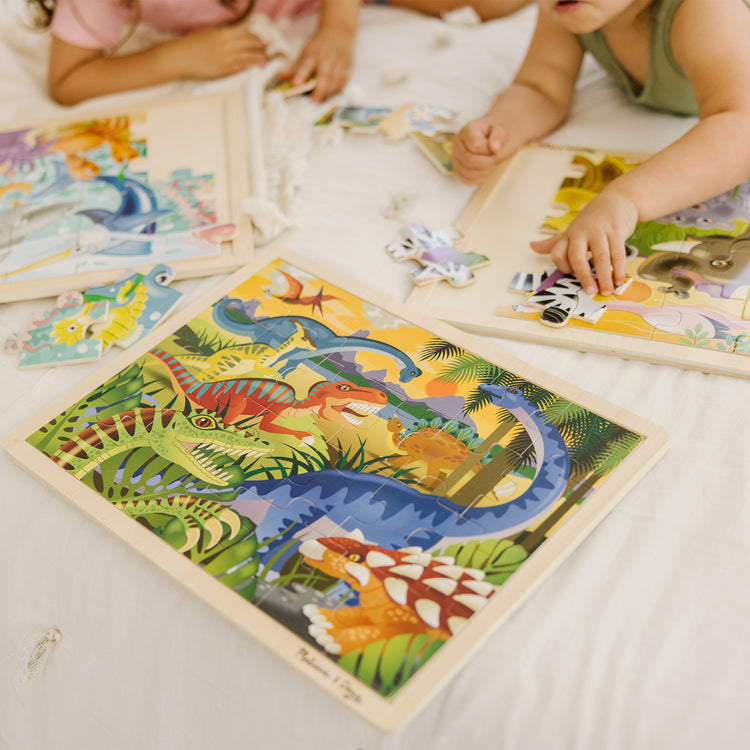 A kid playing with The Melissa & Doug Jigsaw Puzzle Bundle (Dinosaur,Safari and Ocean)