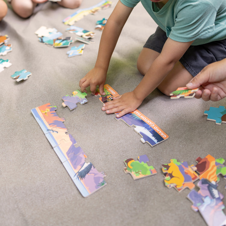 A kid playing with The Melissa & Doug Grand Canyon National Park Wooden Jigsaw Puzzle – 24 Pieces, Animal and Plant ID Guide