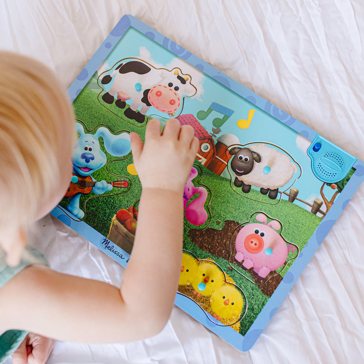 A kid playing with The Melissa & Doug Blue's Clues & You! Wooden Sound Puzzle - Musical Farm (6 Pieces)