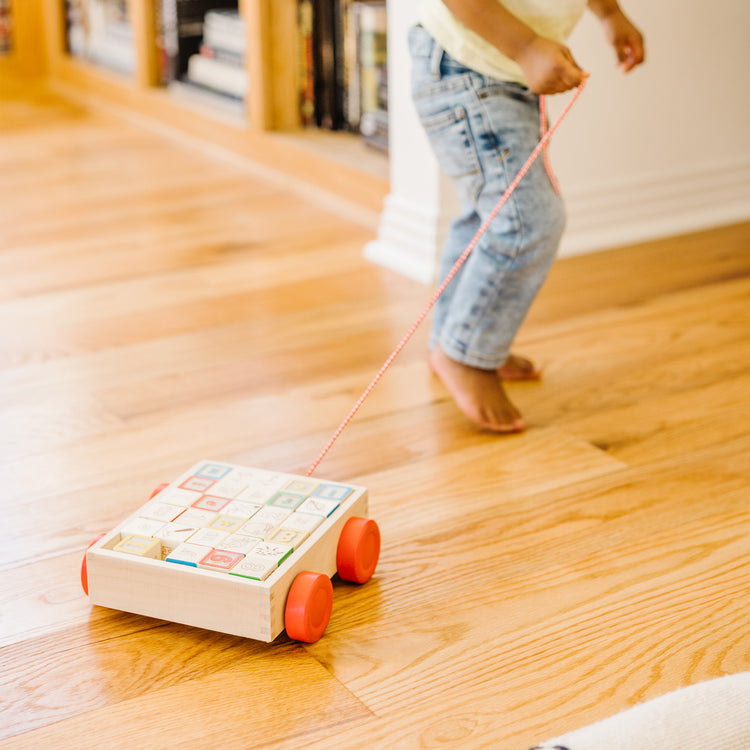 A kid playing with The Melissa & Doug Classic ABC Wooden Block Cart Educational Toy With 30 1-Inch Solid Wood Blocks