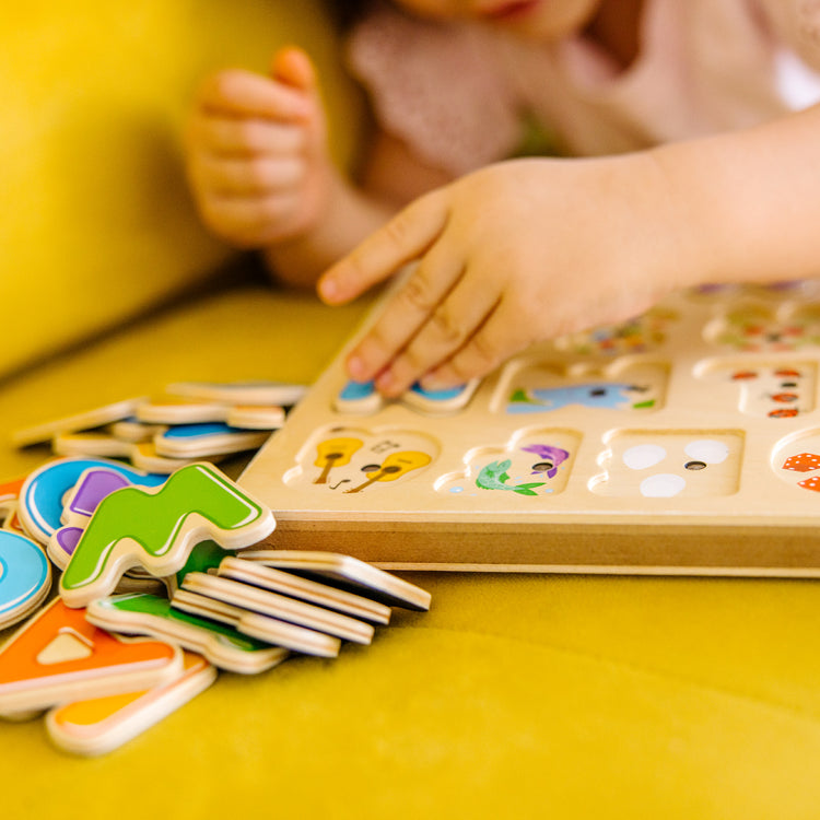 A kid playing with The Melissa & Doug Wooden Alphabet Sound Puzzle - Wooden Puzzle With Sound Effects (26 pcs)