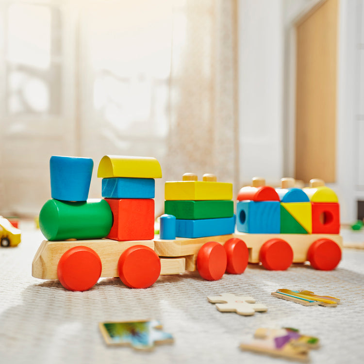 A kid playing with The Melissa & Doug Wooden Stacking Train Learning Toy Vehicle With 18 Connecting Pcs