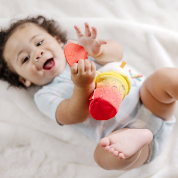 A kid playing with The Melissa & Doug Multi-Sensory Bubble Tea Take-Along Clip-On Infant Toy