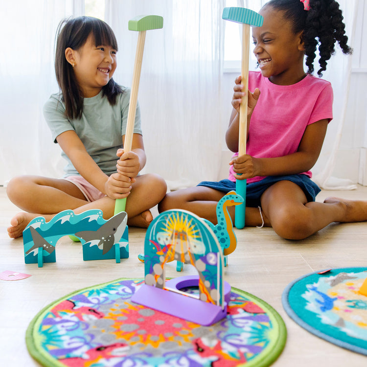 A kid playing with The Melissa & Doug Fun at the Fair! Mini Golf Play Set – 3 Multi-Themed Holes and Wooden Obstacles