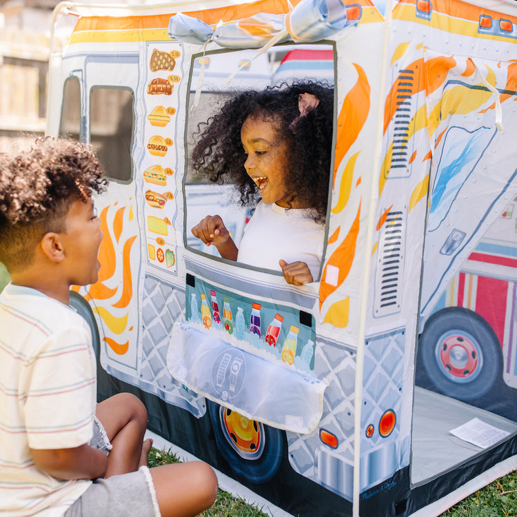 A kid playing with The Melissa & Doug Fabric Double-Sided Food Truck Play Tent - Ice Cream And BBQ