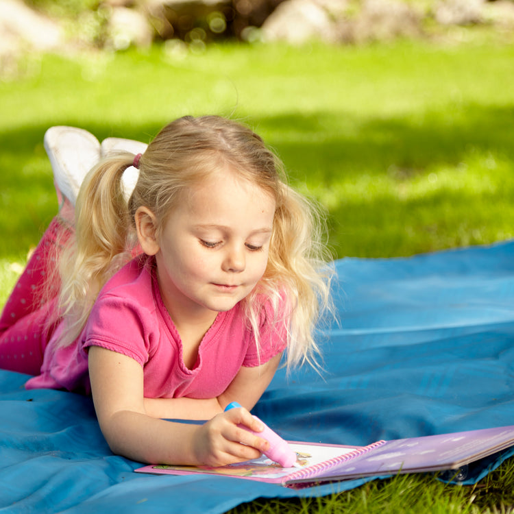 A kid playing with The Melissa & Doug On the Go Water Wow! Reusable Water-Reveal Activity Pad - Fairy Tale