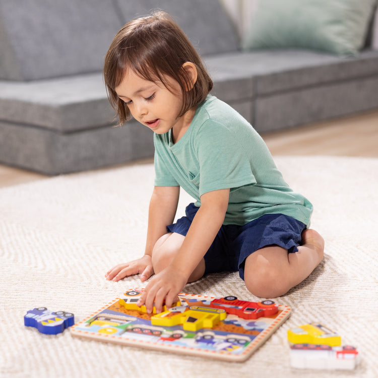 A kid playing with The Melissa & Doug Construction Vehicles Wooden Chunky Puzzle (6 pcs)