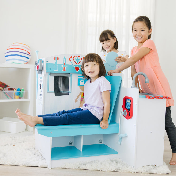 A kid playing with The Melissa & Doug Wooden Get Well Doctor Activity Center - Waiting Room, Exam Room, Check-In Area