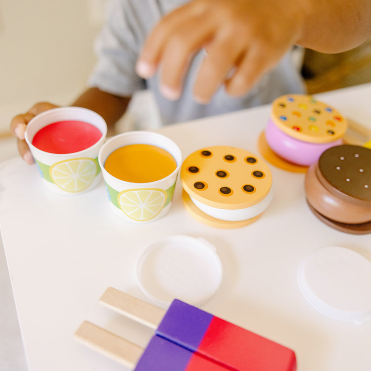 A kid playing with The Melissa & Doug Wooden Frozen Treats Ice Cream Play Set (24 pcs) - Play Food and Accessories