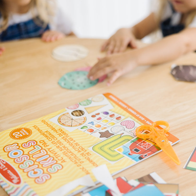 A kid playing with The Melissa & Doug Scissor Skills Activity Book With Pair of Child-Safe Scissors (20 Pages)