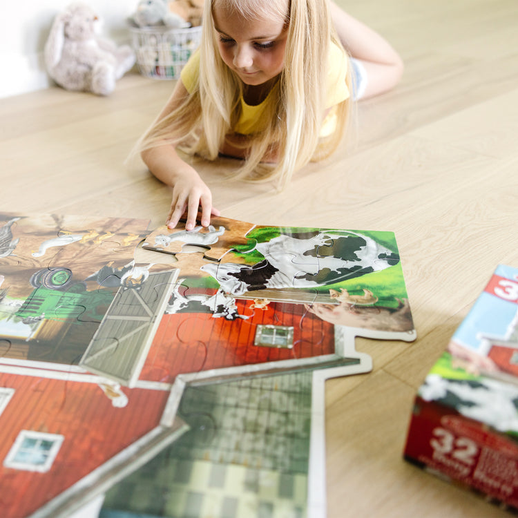 A kid playing with The Melissa & Doug Busy Barn Shaped Jumbo Jigsaw Floor Puzzle (32 pcs, 2 x 3 feet)