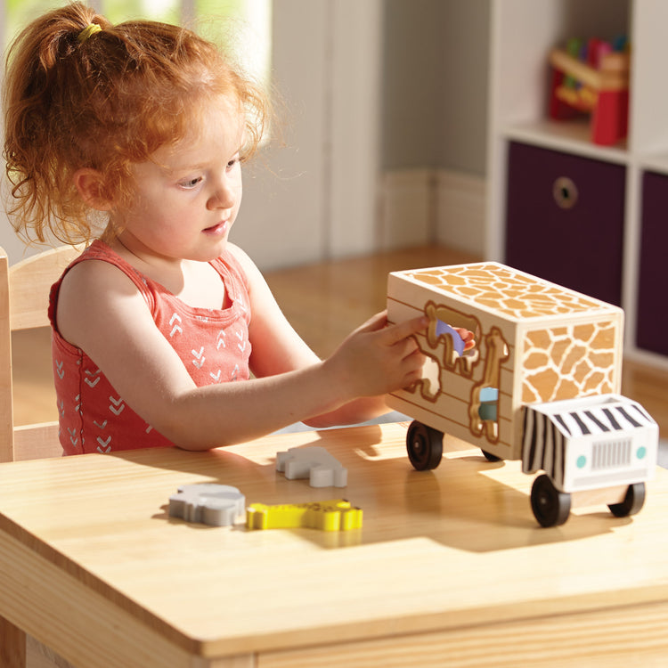 A kid playing with The Melissa & Doug Animal Rescue Shape-Sorting Truck - Wooden Toy With 7 Animals and 2 Play Figures