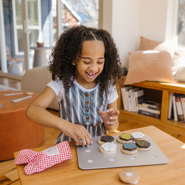 A kid playing with The Melissa & Doug Slice and Bake Wooden Cookie Play Food Set