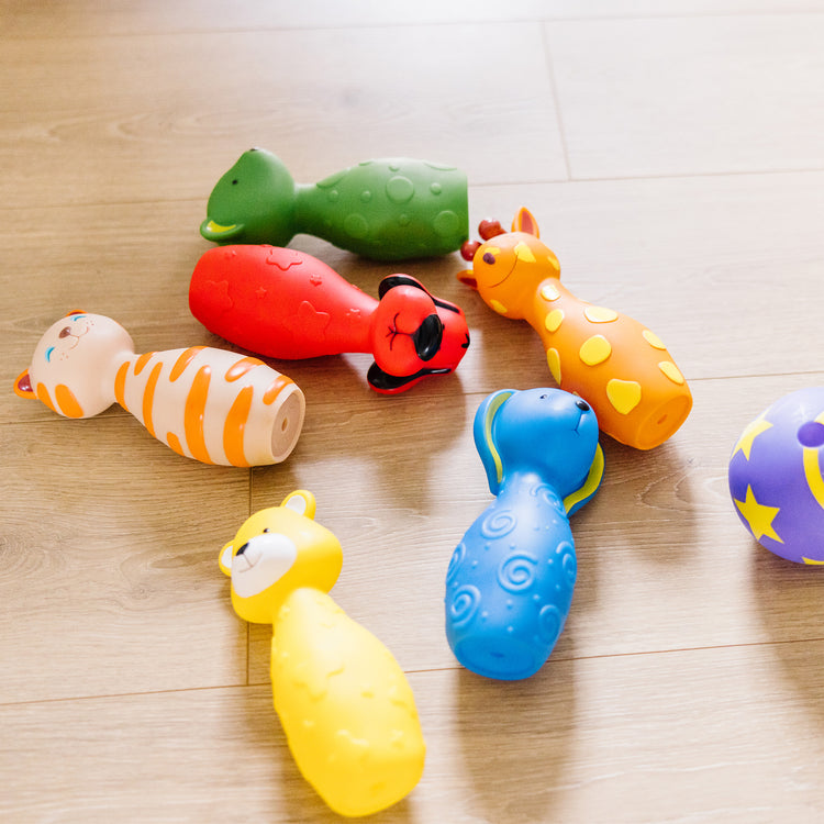 A kid playing with The Melissa & Doug K's Kids Bowling Friends Play Set and Game With 6 Pins and Convenient Carrying Case