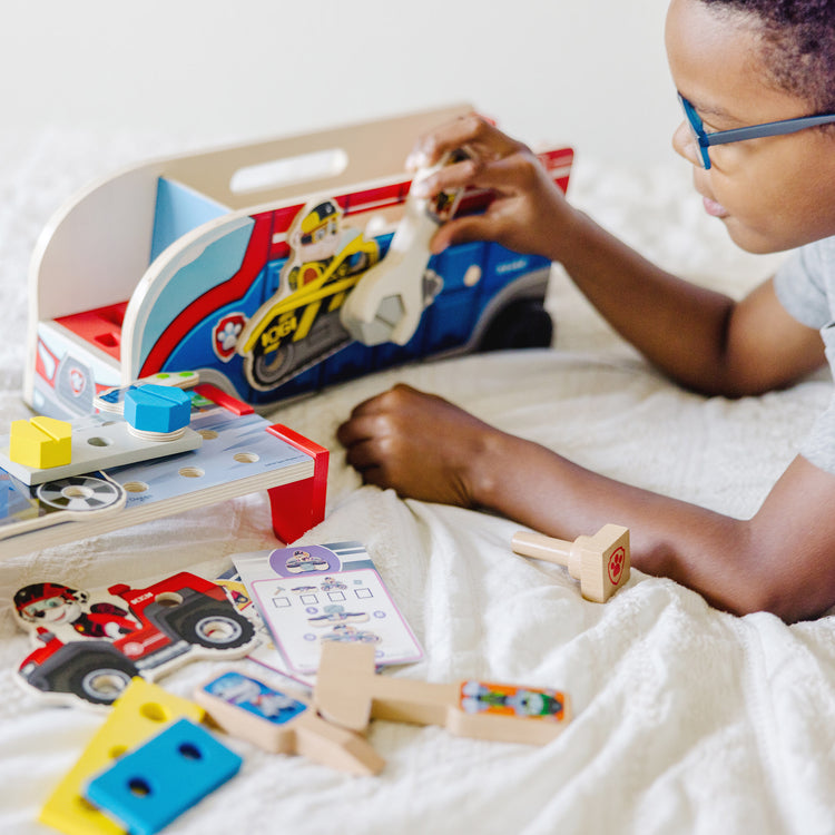 A kid playing with The Melissa & Doug PAW Patrol Match & Build Mission Cruiser