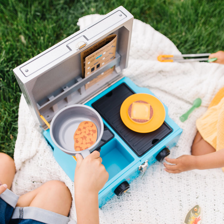 A kid playing with The Melissa & Doug Let’s Explore Camp Stove Play Set – 24 Pieces