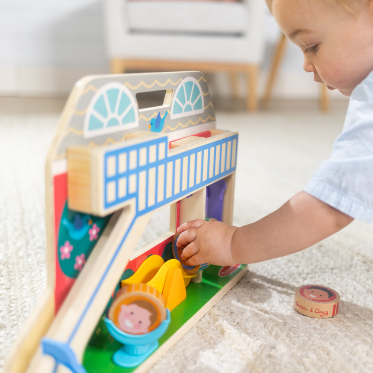 A kid playing with The Melissa & Doug GO Tots Wooden Schoolyard Tumble with 4 Disks