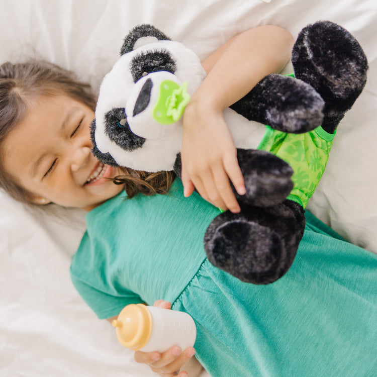 A kid playing with The Melissa & Doug 11-Inch Baby Panda Plush Stuffed Animal with Pacifier, Diaper, Baby Bottle