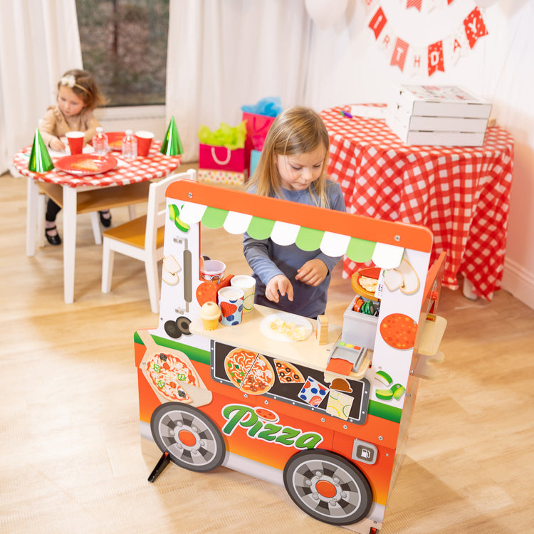 A kid playing with The Melissa & Doug Wooden Pizza Food Truck Activity Center with Play Food, for Boys and Girls 3+