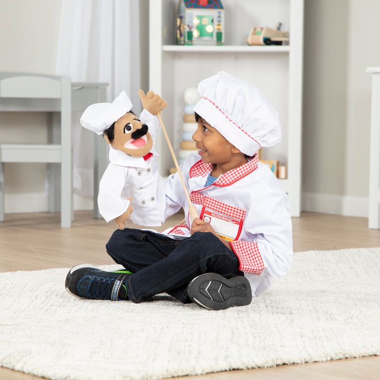 A kid playing with The Melissa & Doug Chef Puppet (Al Dente) with Detachable Wooden Rod