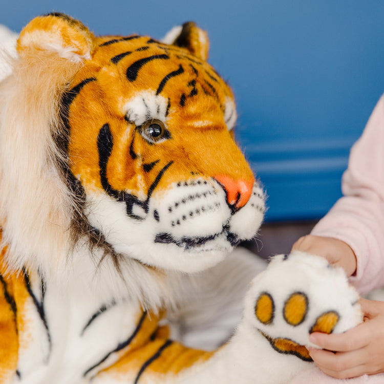 A kid playing with The Melissa & Doug Giant Tiger - Lifelike Stuffed Animal, Over 5 Feet Long (Includes Tail)