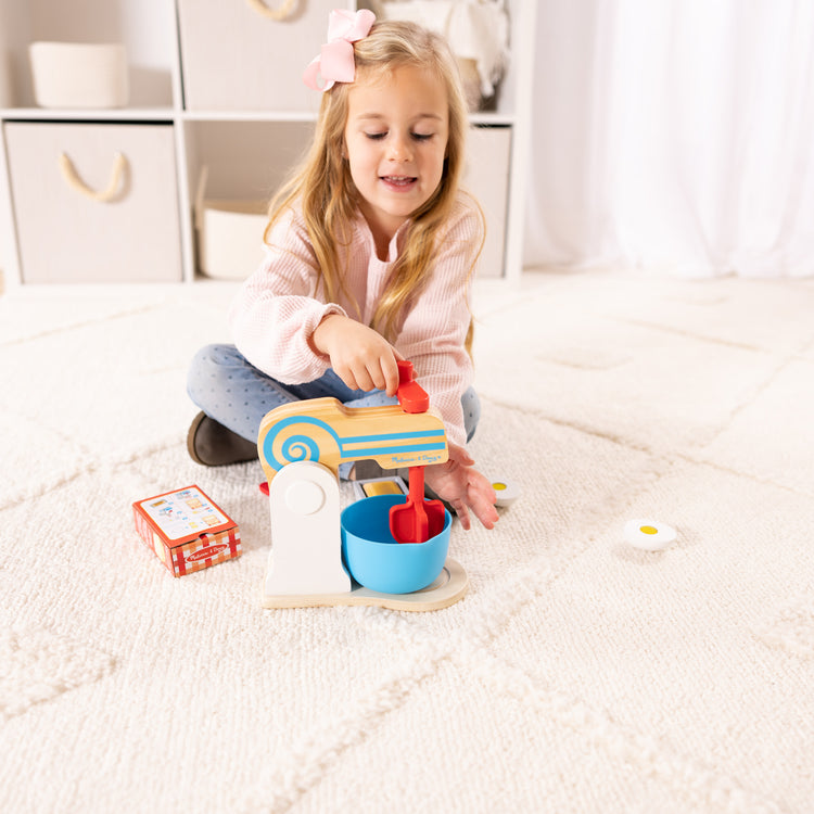 A kid playing with The Melissa & Doug Wooden Make-a-Cake Mixer Set (11 pcs) - Play Food and Kitchen Accessories