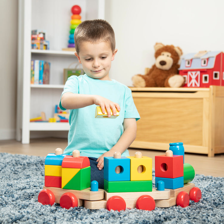 A kid playing with The Melissa & Doug Wooden Jumbo Stacking Train – 4-Color Classic Wooden Toddler Toy (17 pcs)