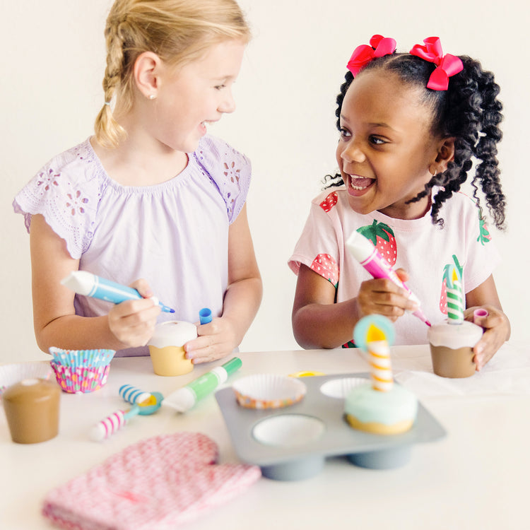 A kid playing with The Melissa & Doug Bake and Decorate Wooden Cupcake Play Food Set