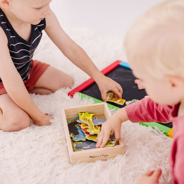 A kid playing with The Melissa & Doug 20 Wooden Animal Magnets in a Box