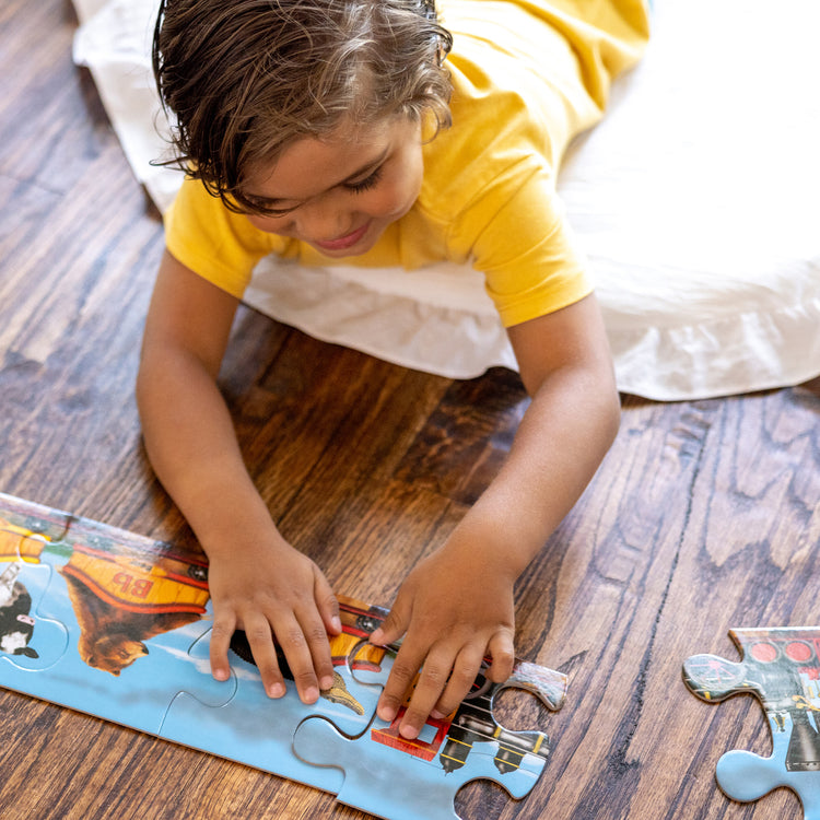 A kid playing with The Melissa & Doug Alphabet Train Jumbo Jigsaw Floor Puzzle - Letters and Animals (28 pcs, 10 feet long)