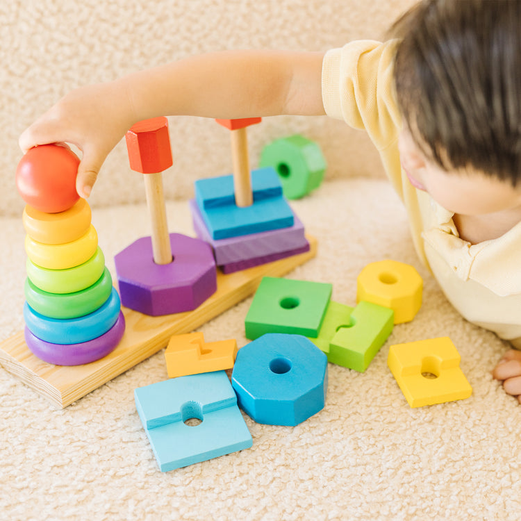 A kid playing with The Melissa & Doug Geometric Stacker - Wooden Educational Toy