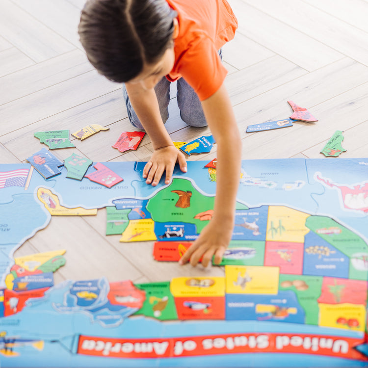 A kid playing with The Melissa & Doug USA Map Floor Puzzle - 51 Pieces (2 x 3 feet)