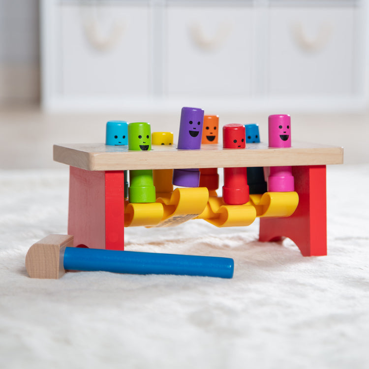 A playroom scene with The Melissa & Doug Deluxe Pounding Bench Wooden Preschool Learning Toy With Mallet