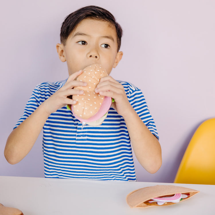 A kid playing with The Melissa & Doug Felt Food Sandwich Play Food Set (33 pcs)