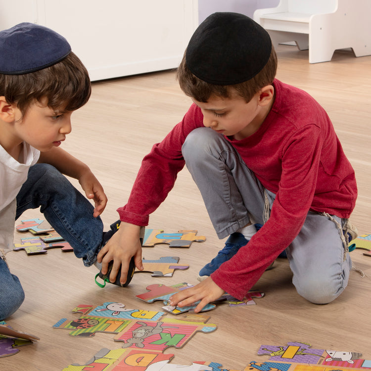 A kid playing with The Melissa & Doug Natural Play Giant Floor Puzzle: ABC Animals (35 Pieces)