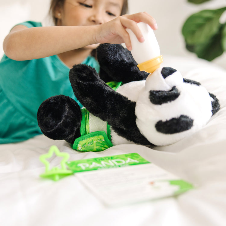 A kid playing with The Melissa & Doug 11-Inch Baby Panda Plush Stuffed Animal with Pacifier, Diaper, Baby Bottle