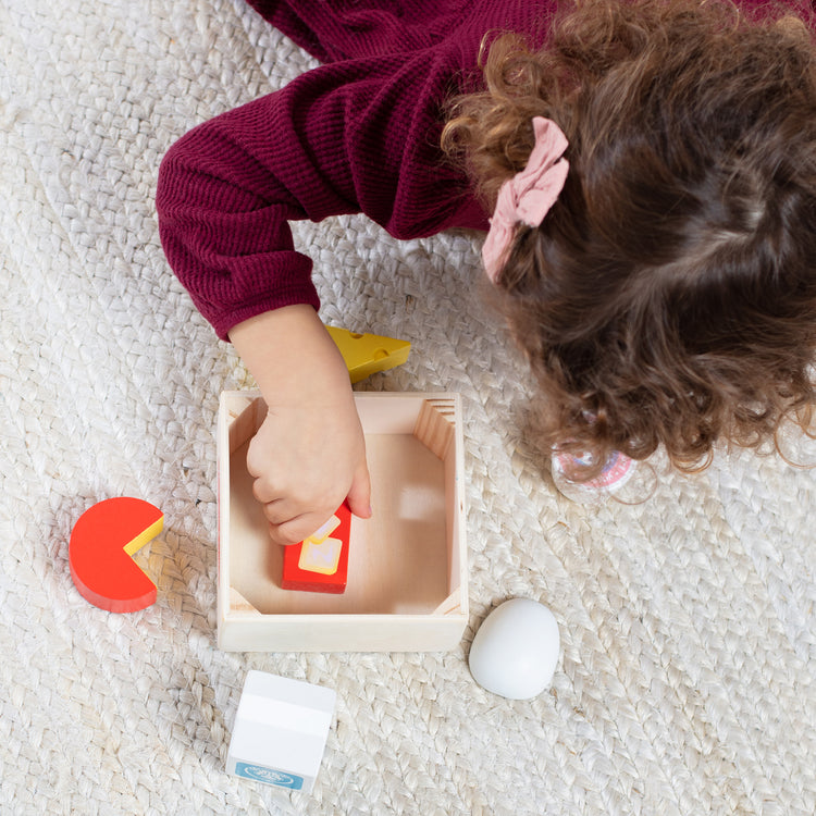 A kid playing with The Melissa & Doug Wooden Food Groups Play Food Set – Dairy