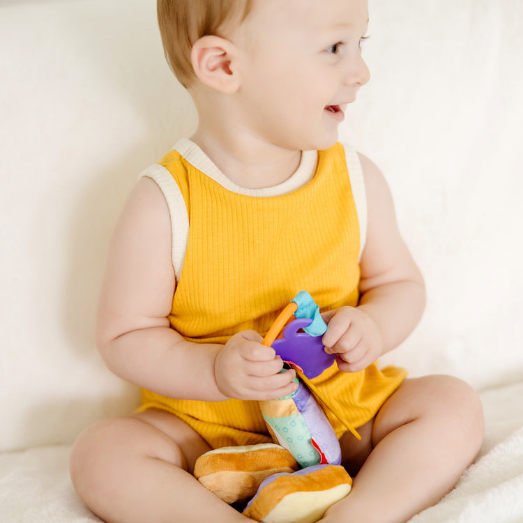 A kid playing with The Melissa & Doug Multi-Sensory PB&J Take-Along Clip-On Infant Toy