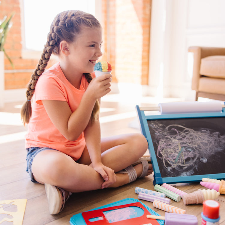 A kid playing with The Melissa & Doug Ice Cream Shop Multi-Colored Chalk and Holders Play Set - 33 Pieces, Great Gift for Girls and Boys