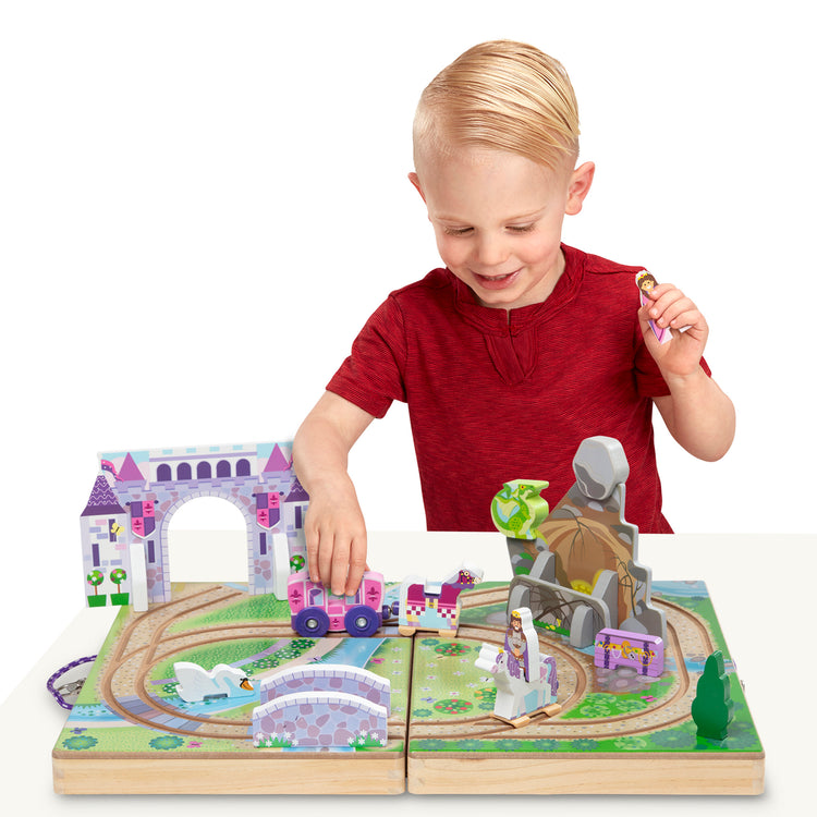 A child on white background with The Melissa & Doug 19-Piece Wooden Take-Along Tabletop Kingdom – Carriage, Horse, Unicorn, Dragon, More