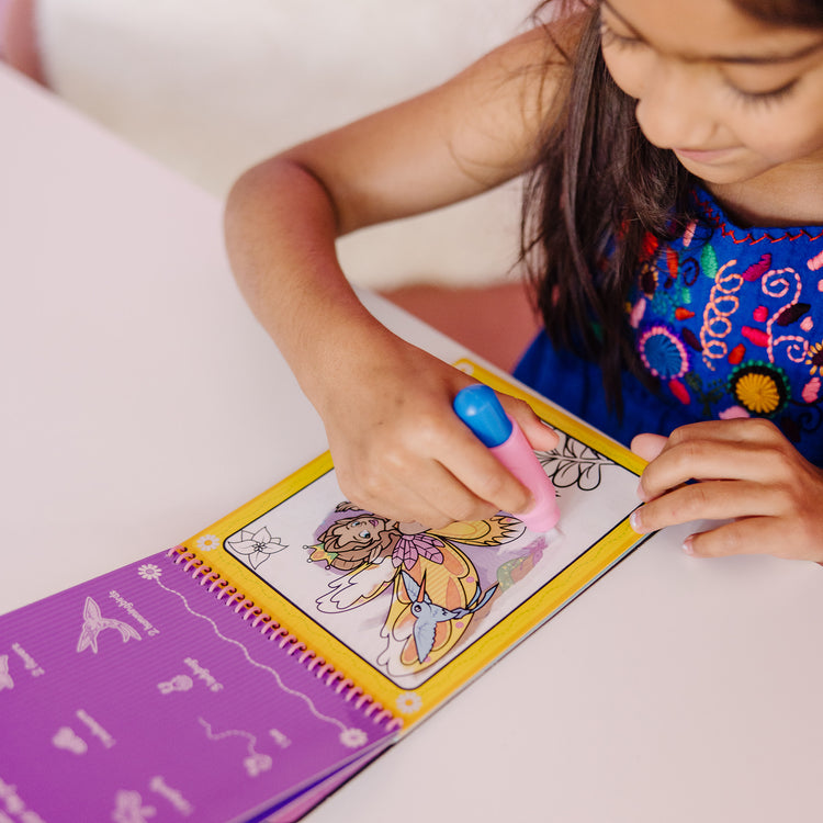 A kid playing with The Melissa & Doug On the Go Water Wow! Reusable Water-Reveal Activity Pad - Fairy Tale