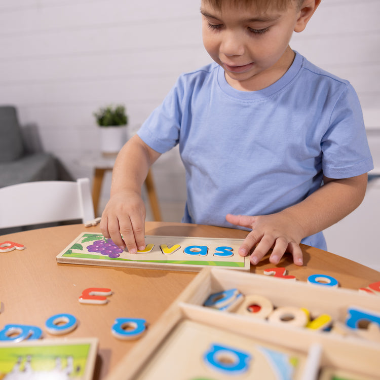 A kid playing with The Melissa & Doug Spanish See & Spell Educational Language Learning Toy