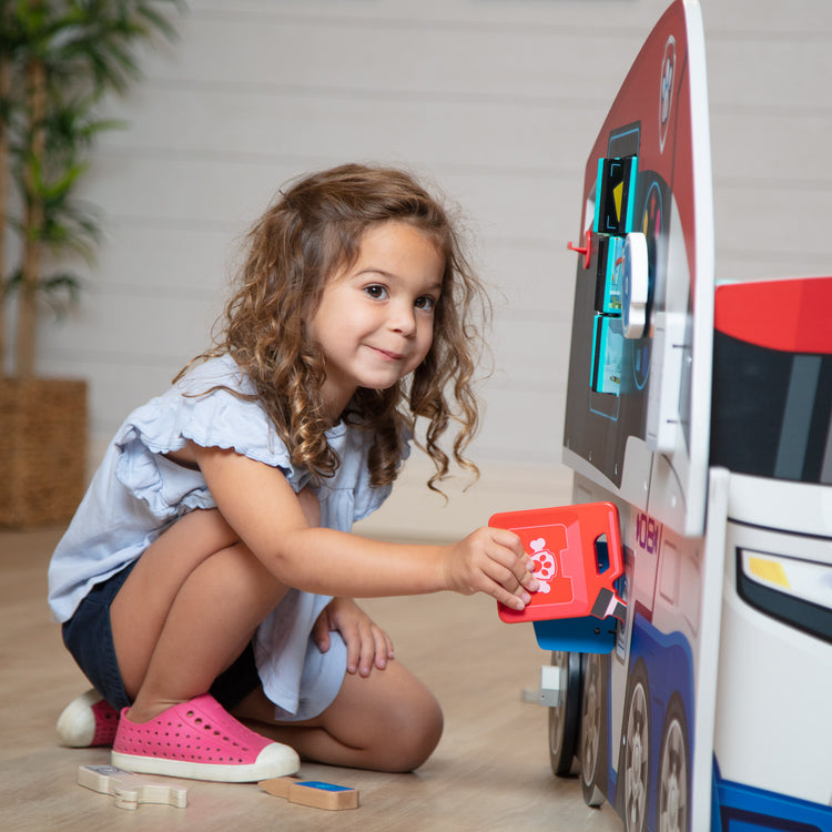 A kid playing with The Melissa & Doug PAW Patrol Wooden PAW Patroller Activity Center Multi-Sided Play Space