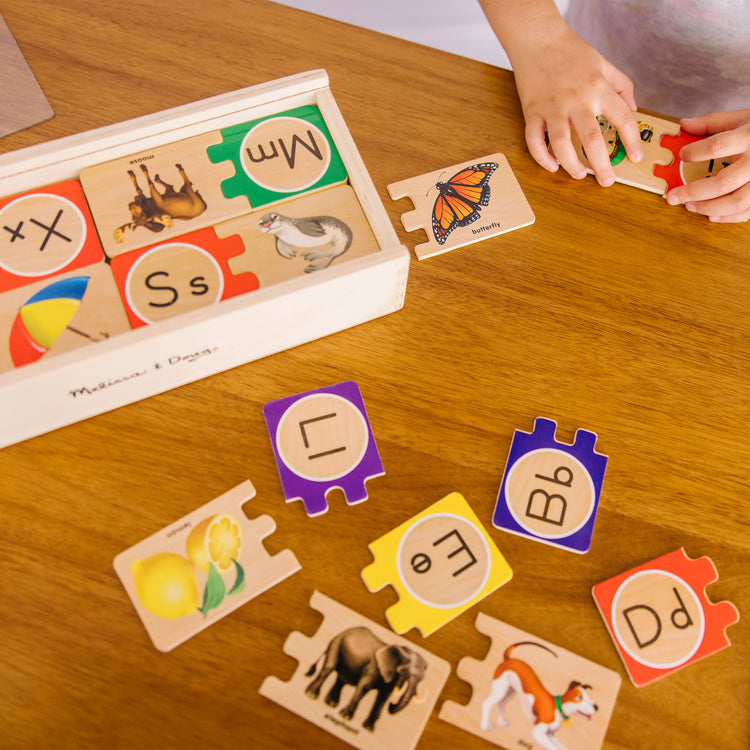 A kid playing with The Melissa & Doug Self-Correcting Alphabet Wooden Puzzles With Storage Box (52 pcs)