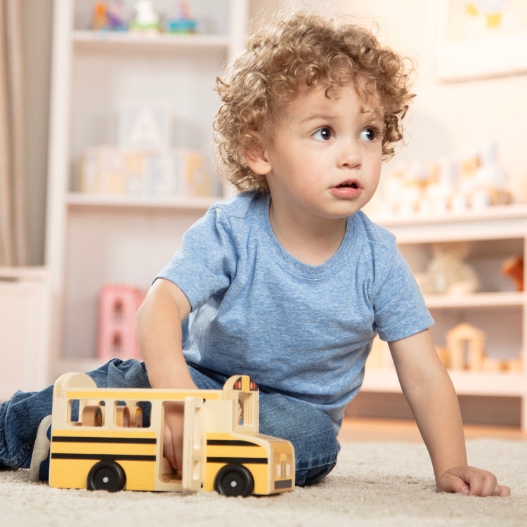 A kid playing with The Melissa & Doug School Bus Wooden Play Set With 7 Play Figures